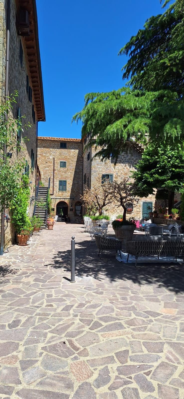 A courtyard with stone flooring, outdoor seating, and stone buildings.
