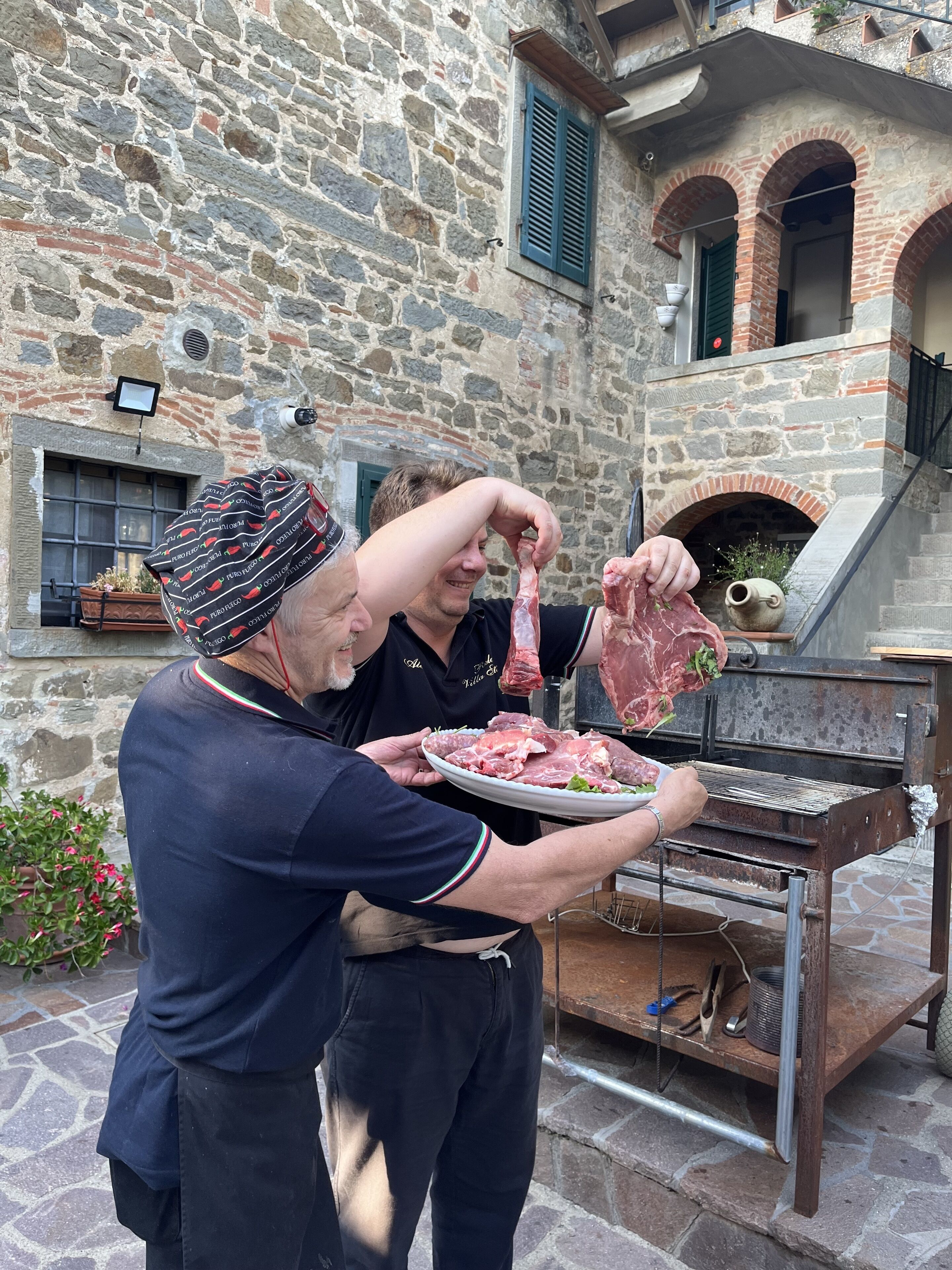 Um edifício de pedra com uma churrasqueira rústica ao ar livre e um prato de carne crua.