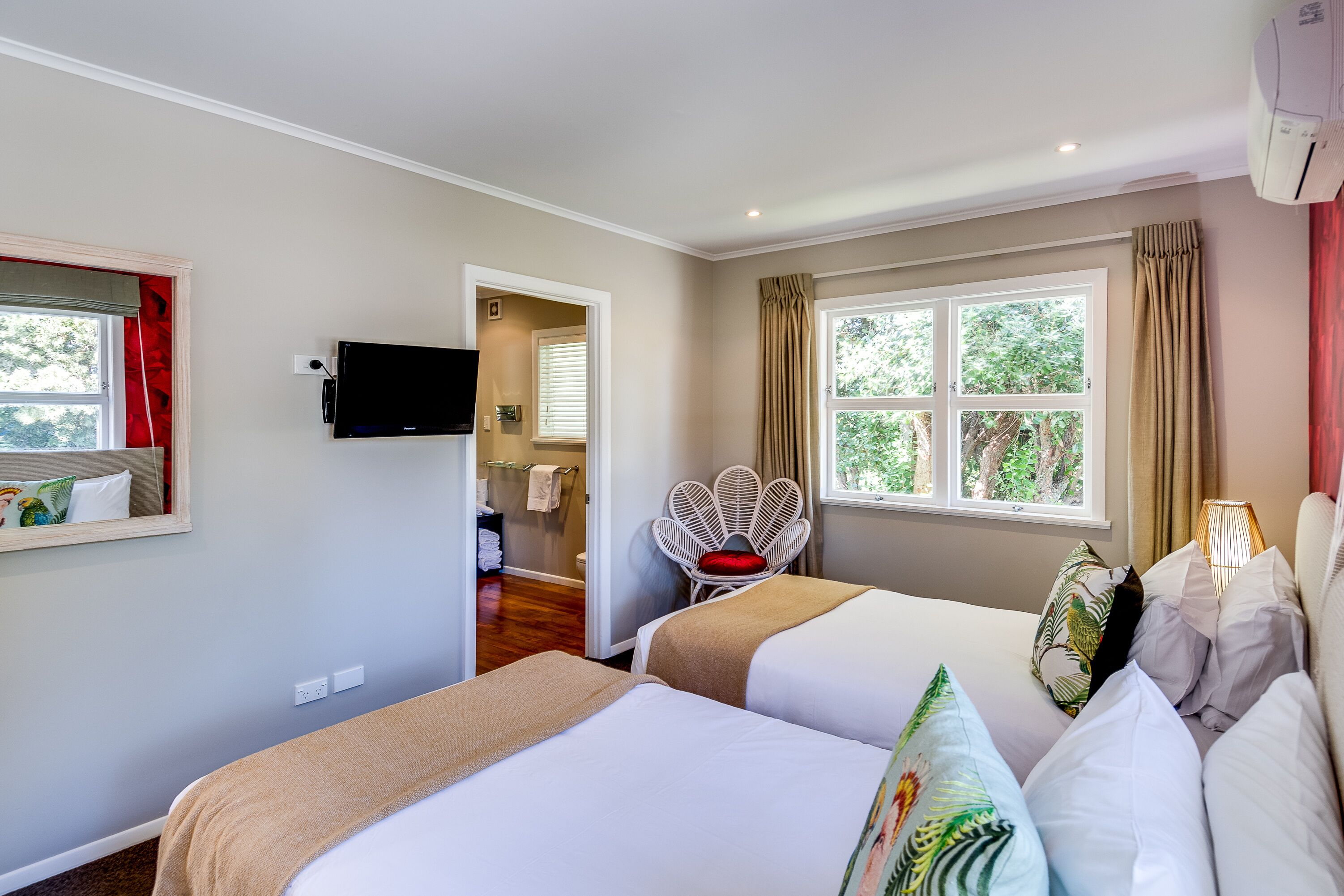 A hotel room with two beds, a television, a chair, and a window with curtains.