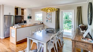 Una cocina moderna con una isla central, sillas blancas y una mesa de comedor.