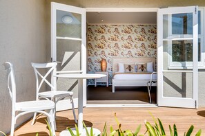 An open patio with a bed, white furniture, and a floral wallpaper interior. - The Farmhouse at Mission Estate (Napier)