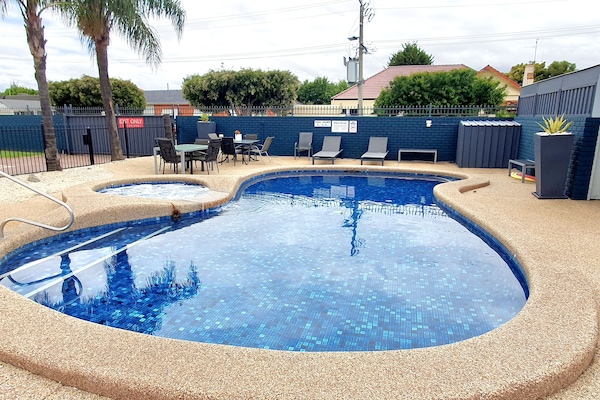Una piscina al aire libre, sillones reclinables de piscina