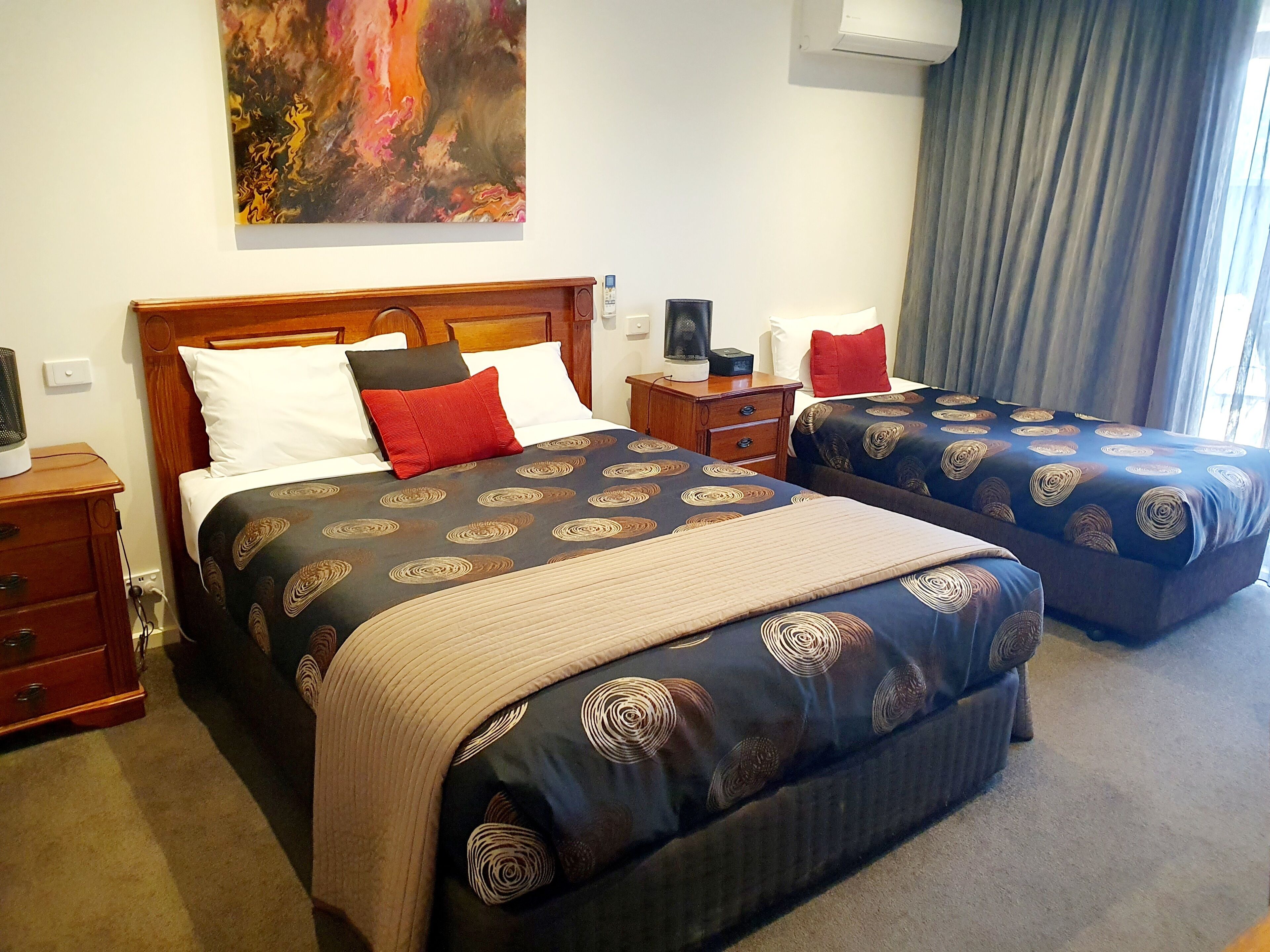 Habitación de hotel con dos camas, una mesita de noche, una lámpara y un cuadro en la pared.