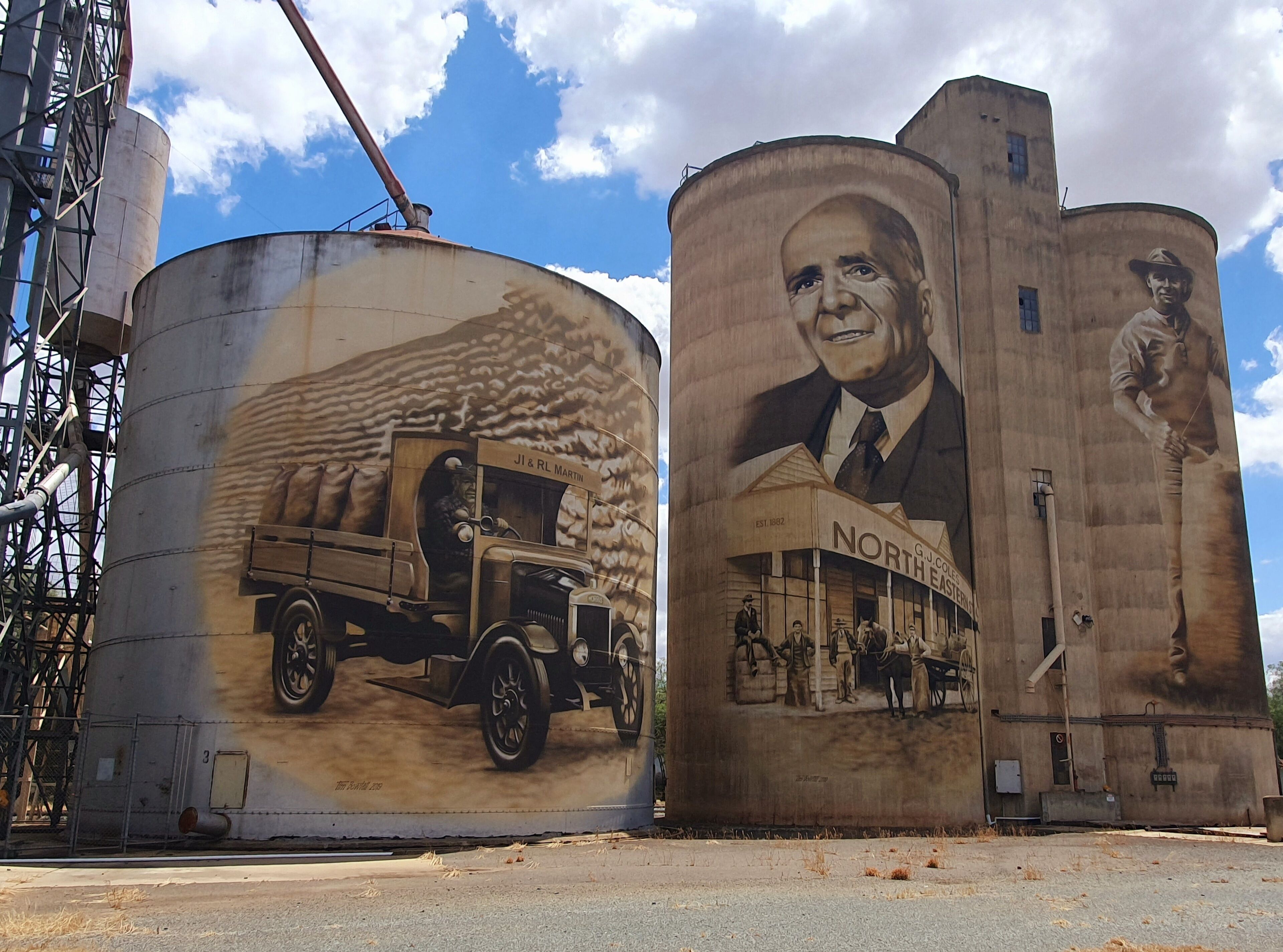 Two large cylindrical silos with murals, one depicting a vintage truck and the other a building labeled 'North East'.