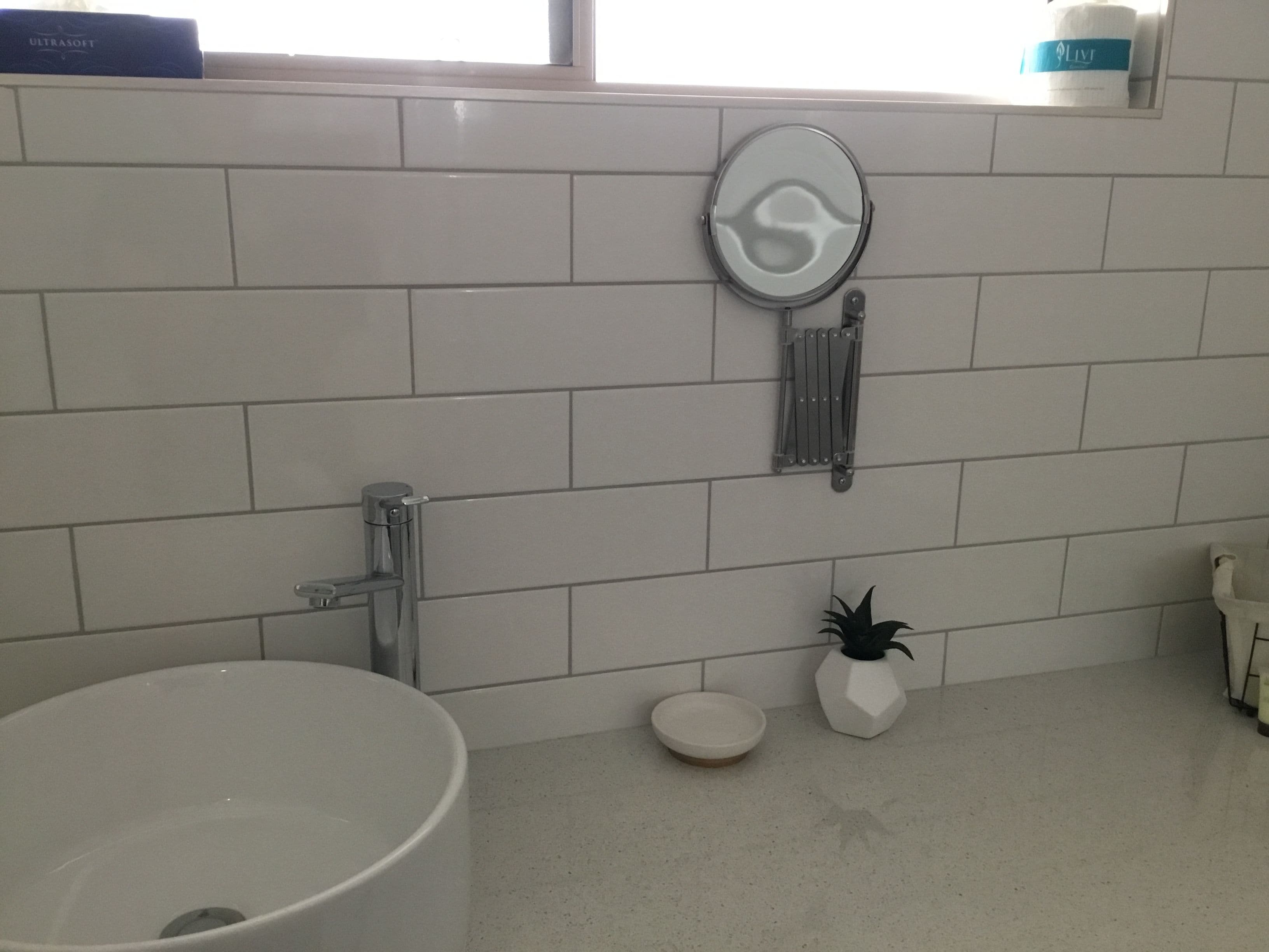A bathroom with a white sink, a mirror, a towel rack, and a small potted plant.