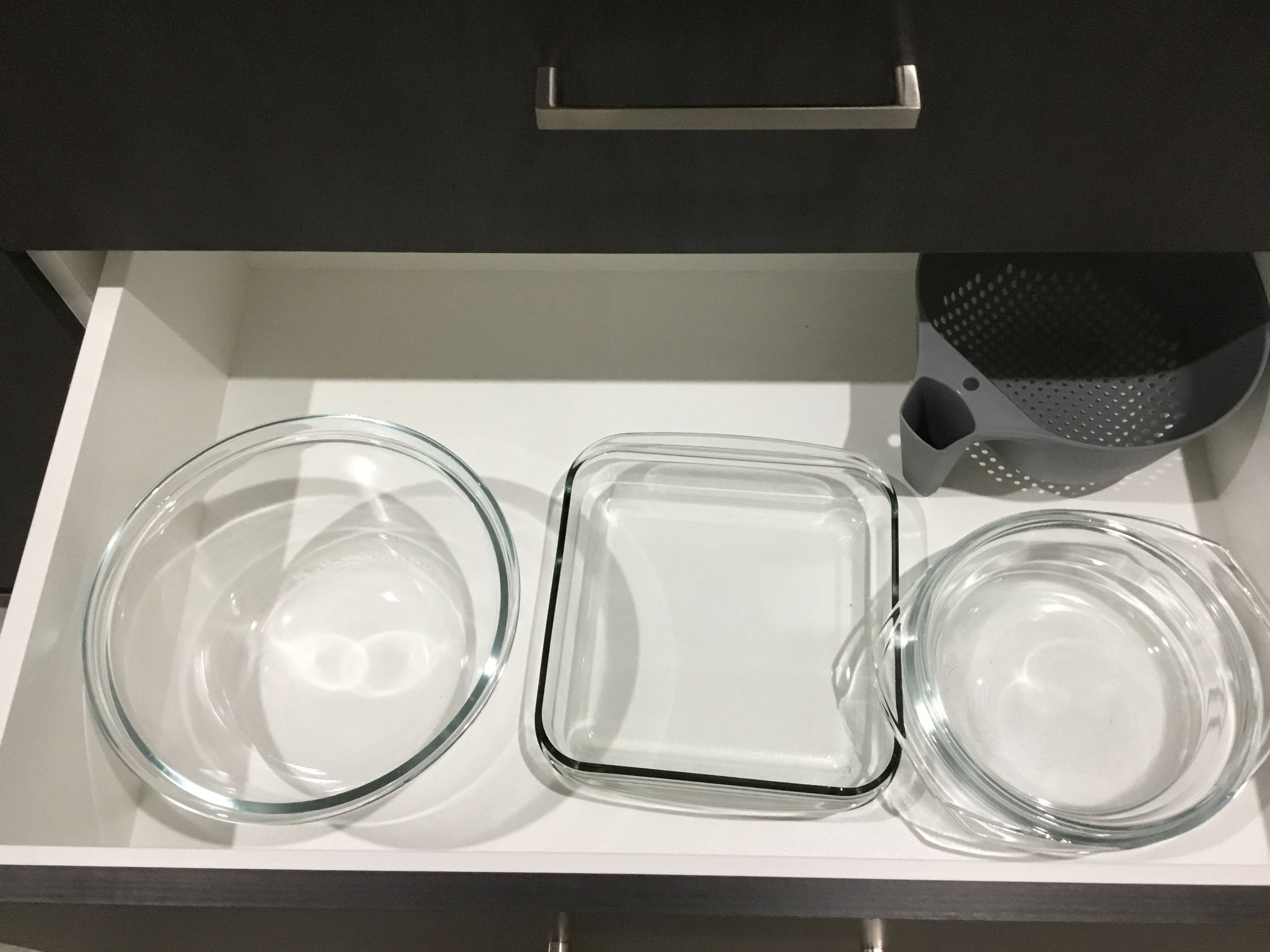 A drawer with three clear glass dishes.