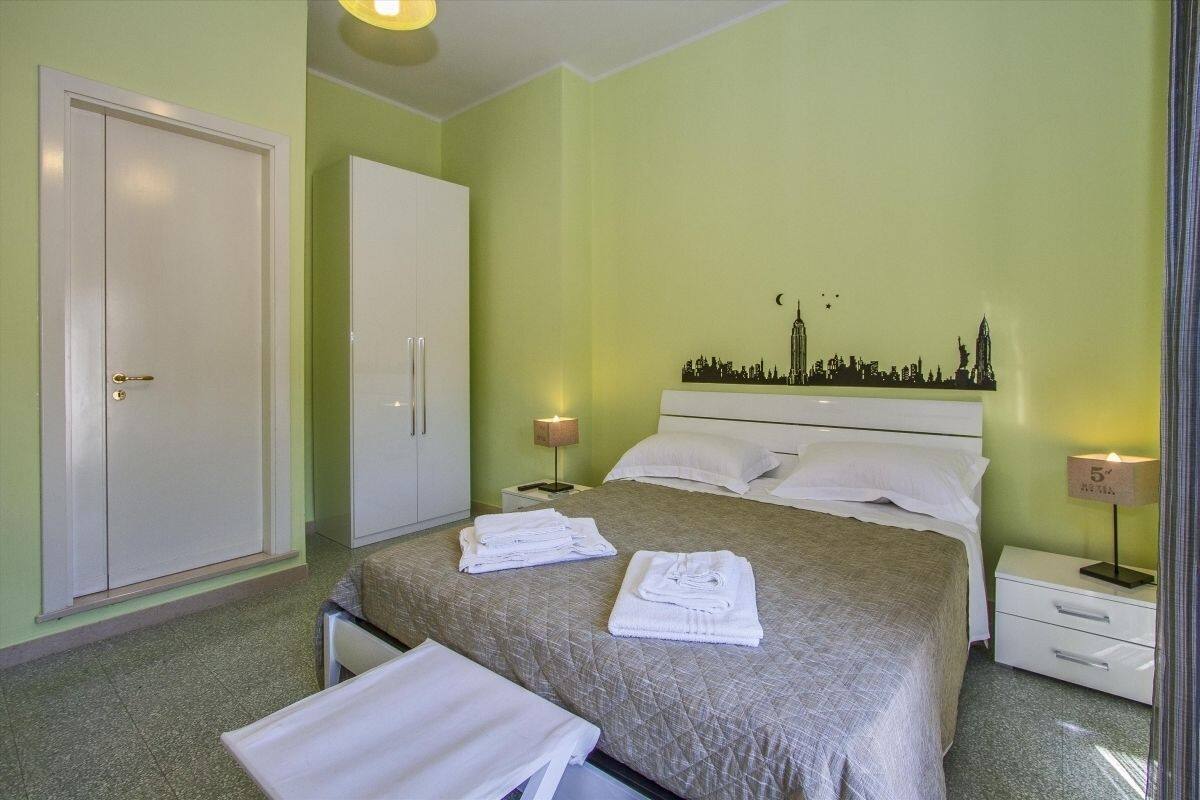 Ein Hotelzimmer mit einem Bett, zwei Nachttischen, einem Kleiderschrank und einer Wanddekoration mit Stadtansicht.