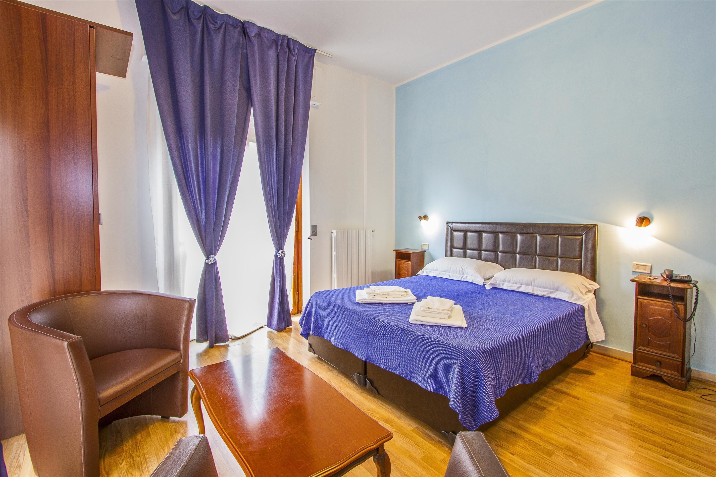 Une chambre à coucher comprenant un lit, une chaise, une table et une table de chevet avec une lampe.