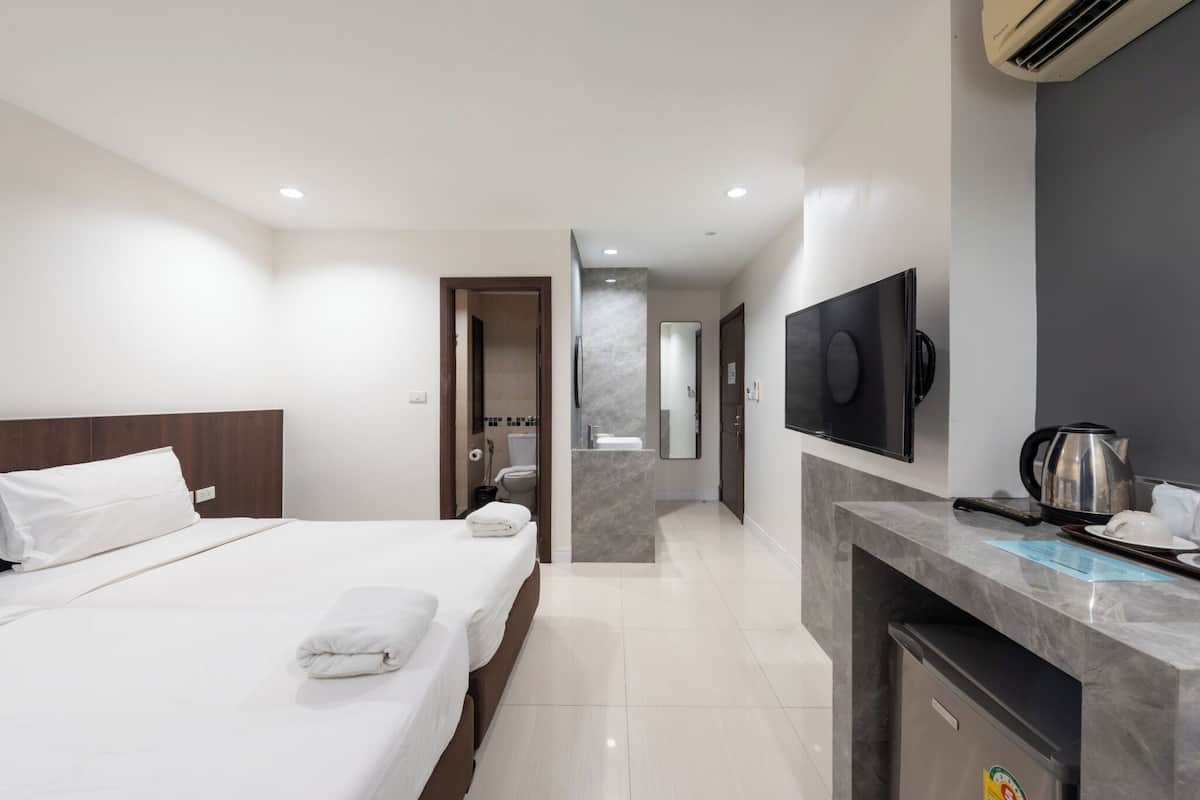 A hotel room with a large bed, a desk with a kettle, and a TV.