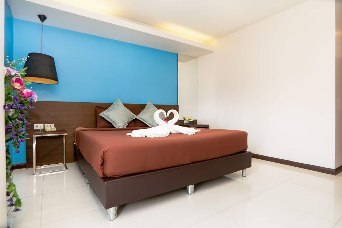 A modern hotel room with a large bed, a nightstand, a lamp, and a decorative flower arrangement.