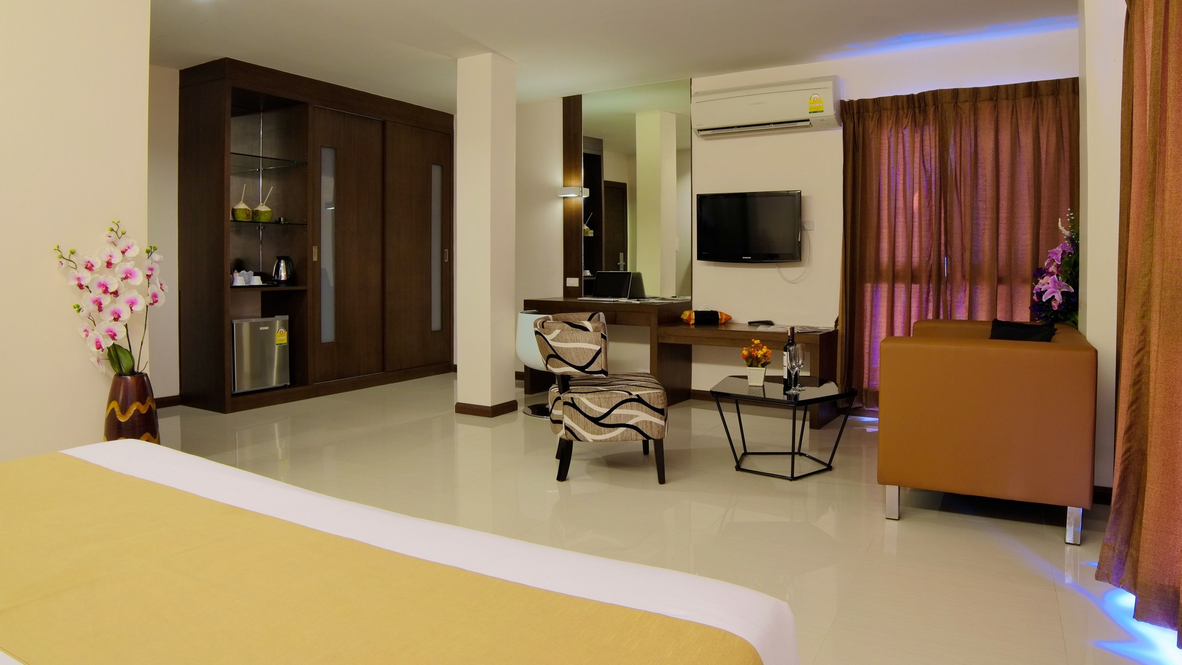Een hotelkamer met een bed, een bureau, een stoel, een televisie en een minibar.