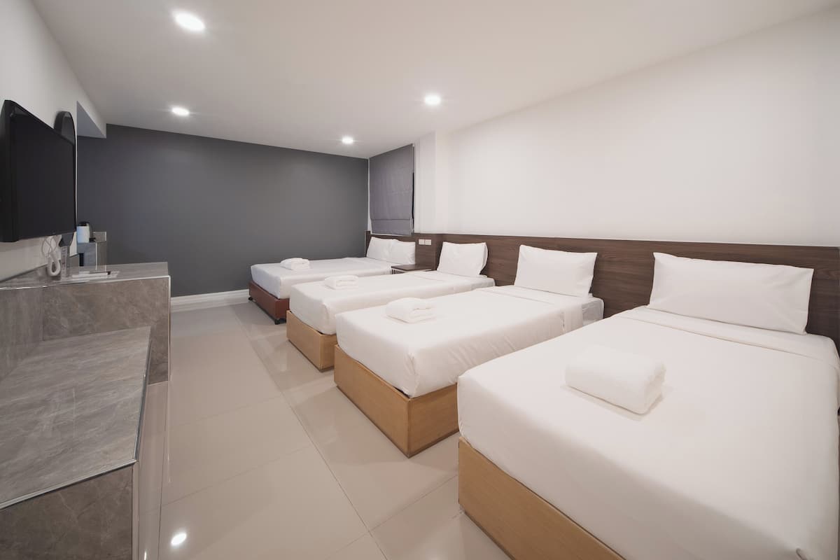 A hotel room with four single beds, a flat-screen TV, and a marble-tiled vanity.