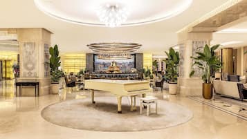 A luxurious lobby with a grand piano, a bar area, and elegant decor.