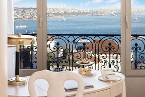 Un balcon avec une table dressée pour le thé, d’où l’on peut admirer le paysage urbain et la mer.