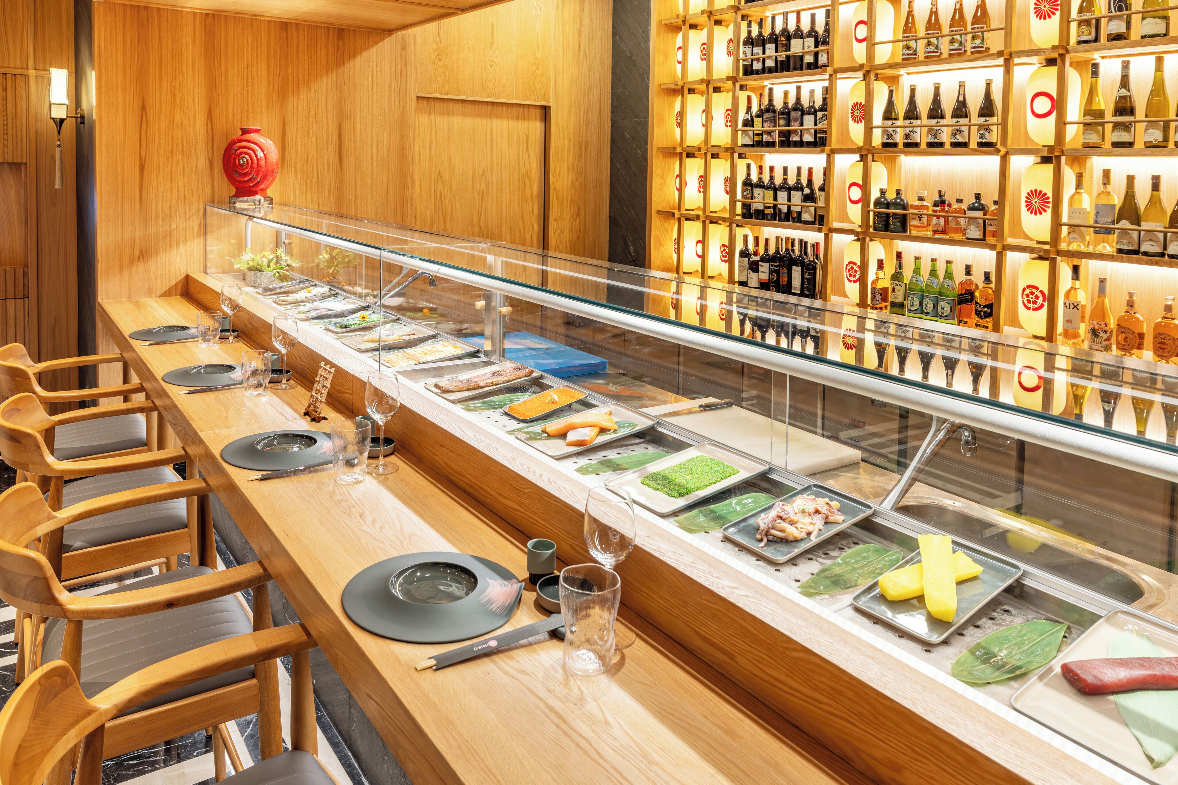 A buffet setup with multiple serving stations, a variety of food items, and a selection of beverages behind a glass partition.