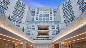 Een modern hotel met een centraal gelegen zwembad, meerdere balkons en een symmetrisch ontwerp.