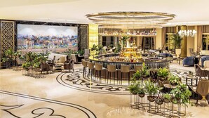 A luxurious lobby with a central bar, seating areas, and a large screen displaying a cityscape. - CVK Park Bosphorus Hotel Istanbul (Istanbul)