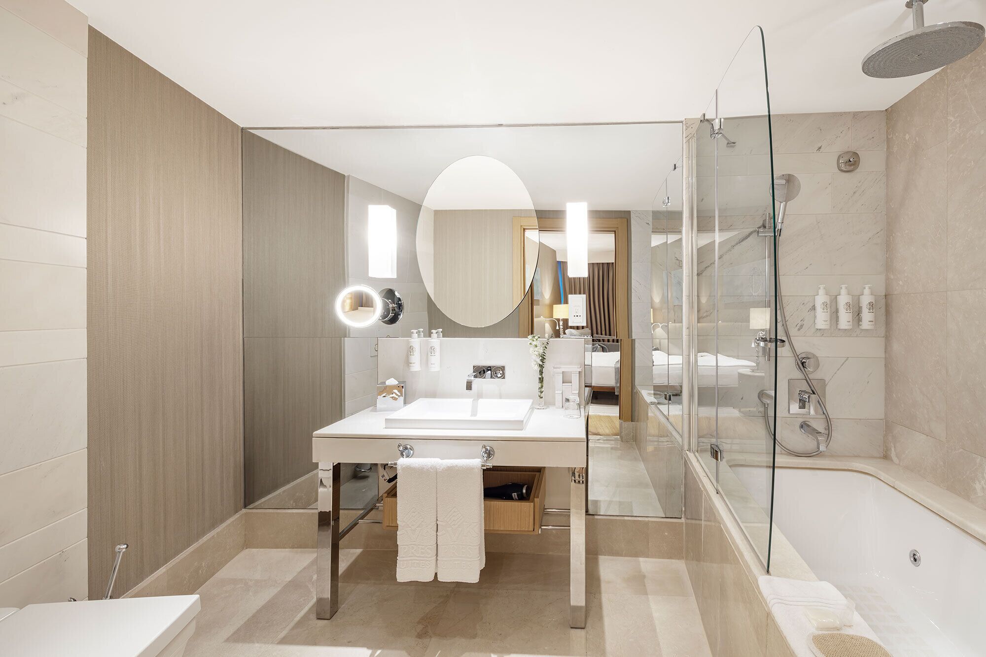 A modern bathroom with a glass-enclosed shower, a large mirror, and a vanity with a sink and towel rack.
