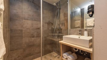 Un bagno moderno con cabina doccia in vetro, lavandino bianco e porta asciugamani.