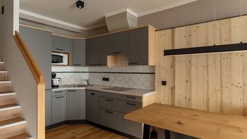 Una cocina moderna con armarios grises, una mesa de madera y un salpicadero de azulejos.
