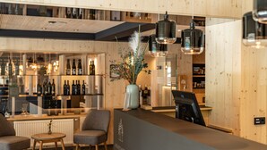 A reception area with a wooden interior, a bar with bottles, and seating. - Ferienalm Panorama Hotel & Apartments (Schladming)