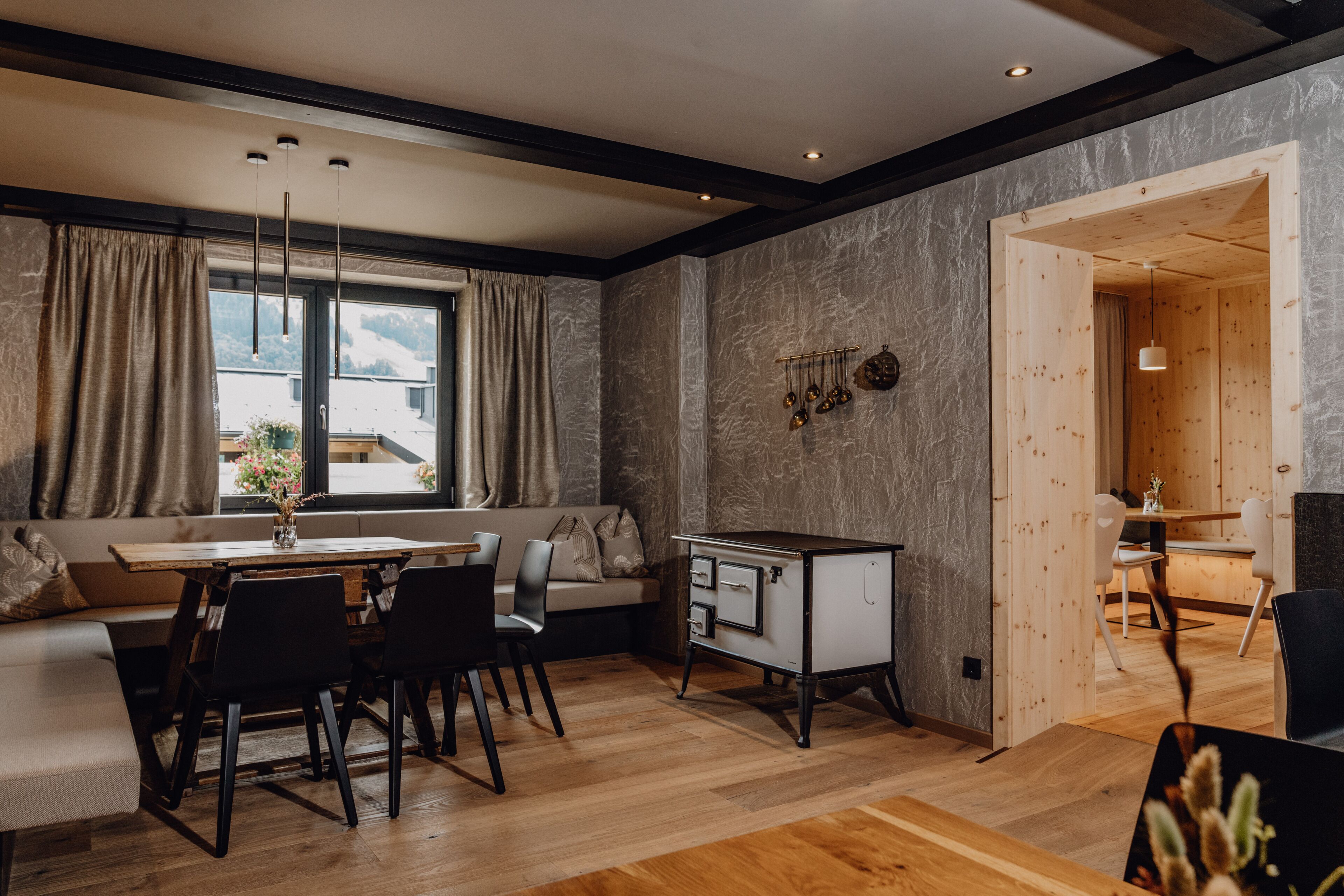 A modern kitchen with a wooden dining table, black chairs, and a built-in white cabinet.