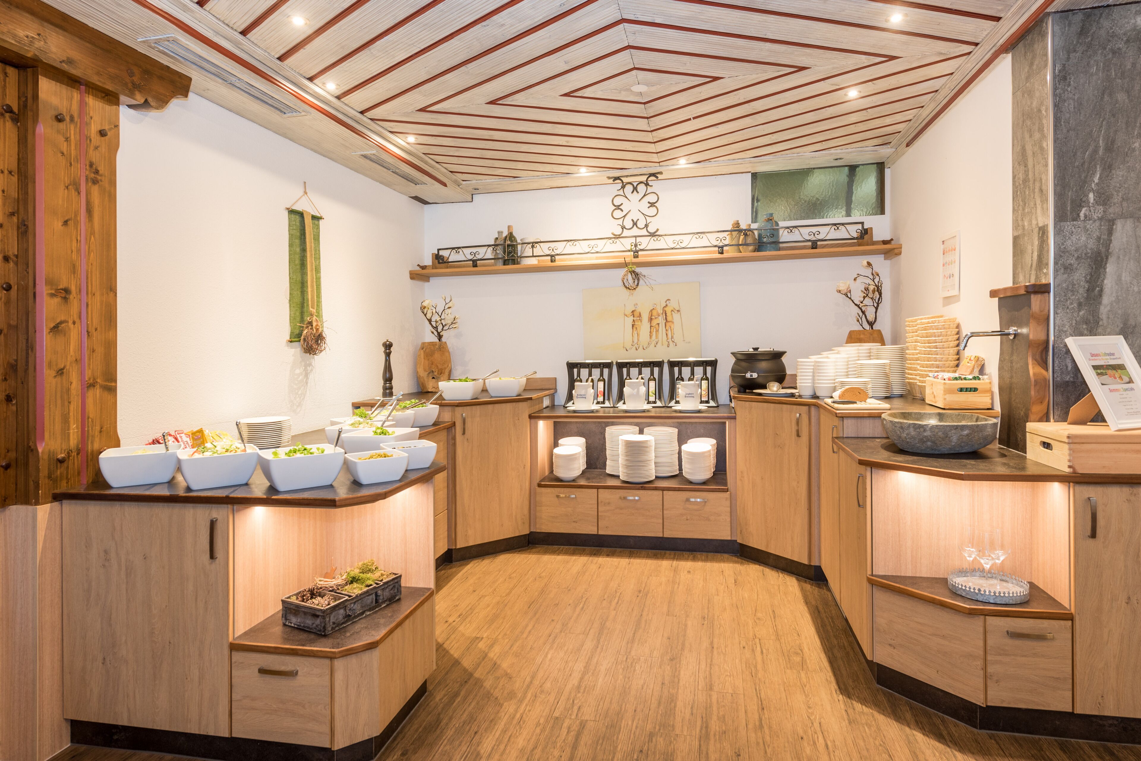 A buffet setup with various food items and serving dishes, wooden cabinets, and a decorative ceiling.