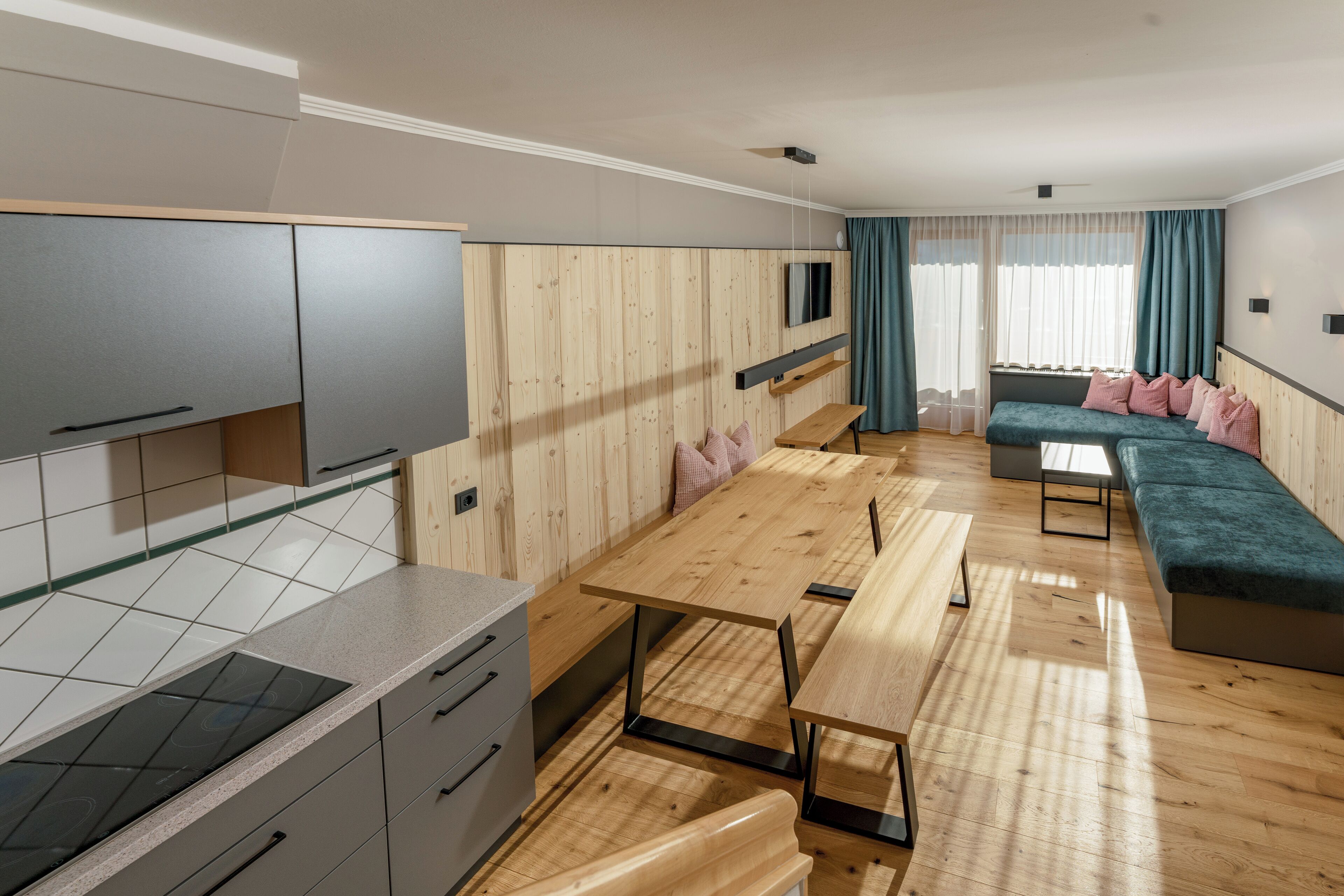 Eine moderne Küche mit Einbauherd, grauen Schränken und einem Holztisch.