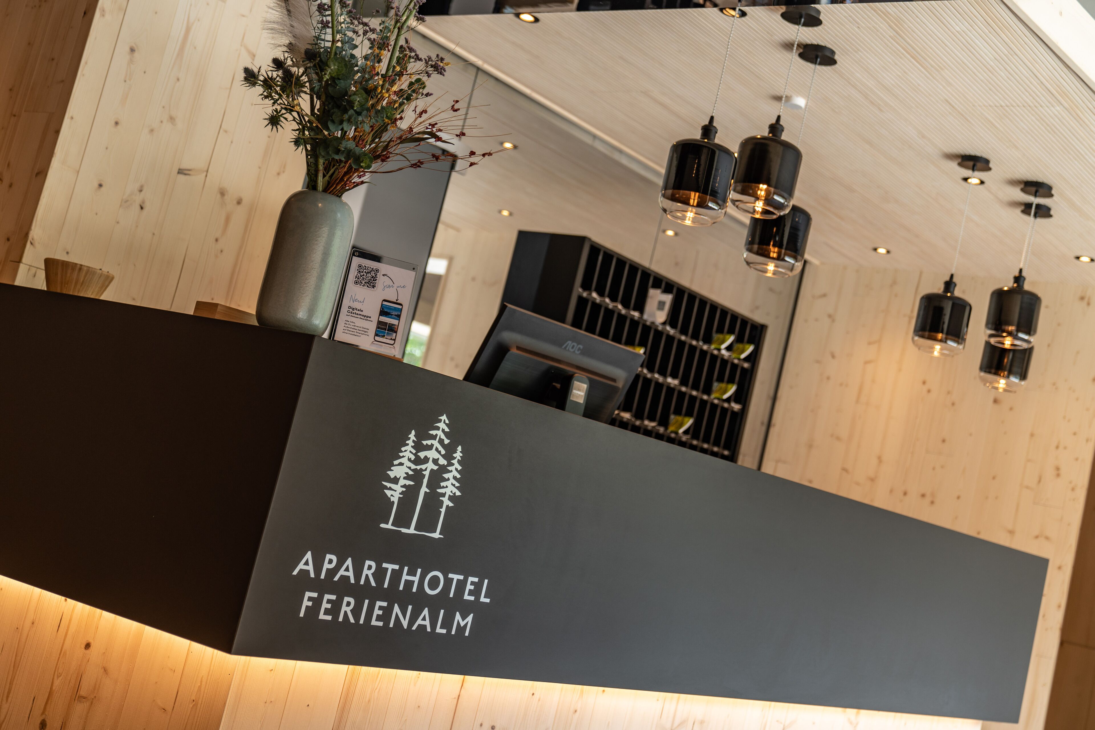 A reception desk with a logo for 'Aparthotel Ferienalm' and a QR code.