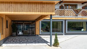 A modern building with a wooden facade, large windows, and a covered entrance area. - Ferienalm Panorama Hotel & Apartments (Schladming)