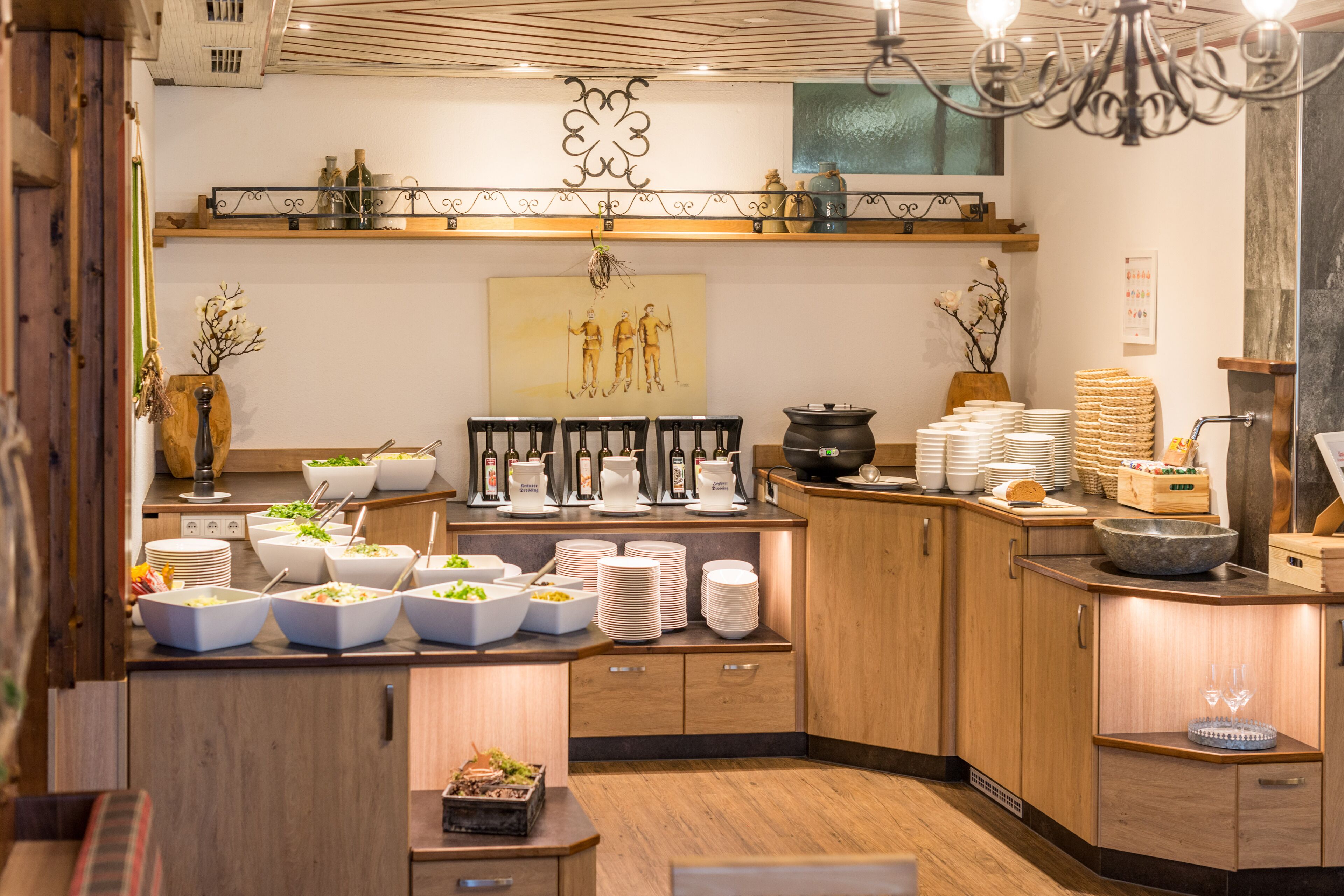 Une cuisine bien éclairée, dotée de meubles en bois, où l’on trouve une variété de plats et un élément décoratif mural.