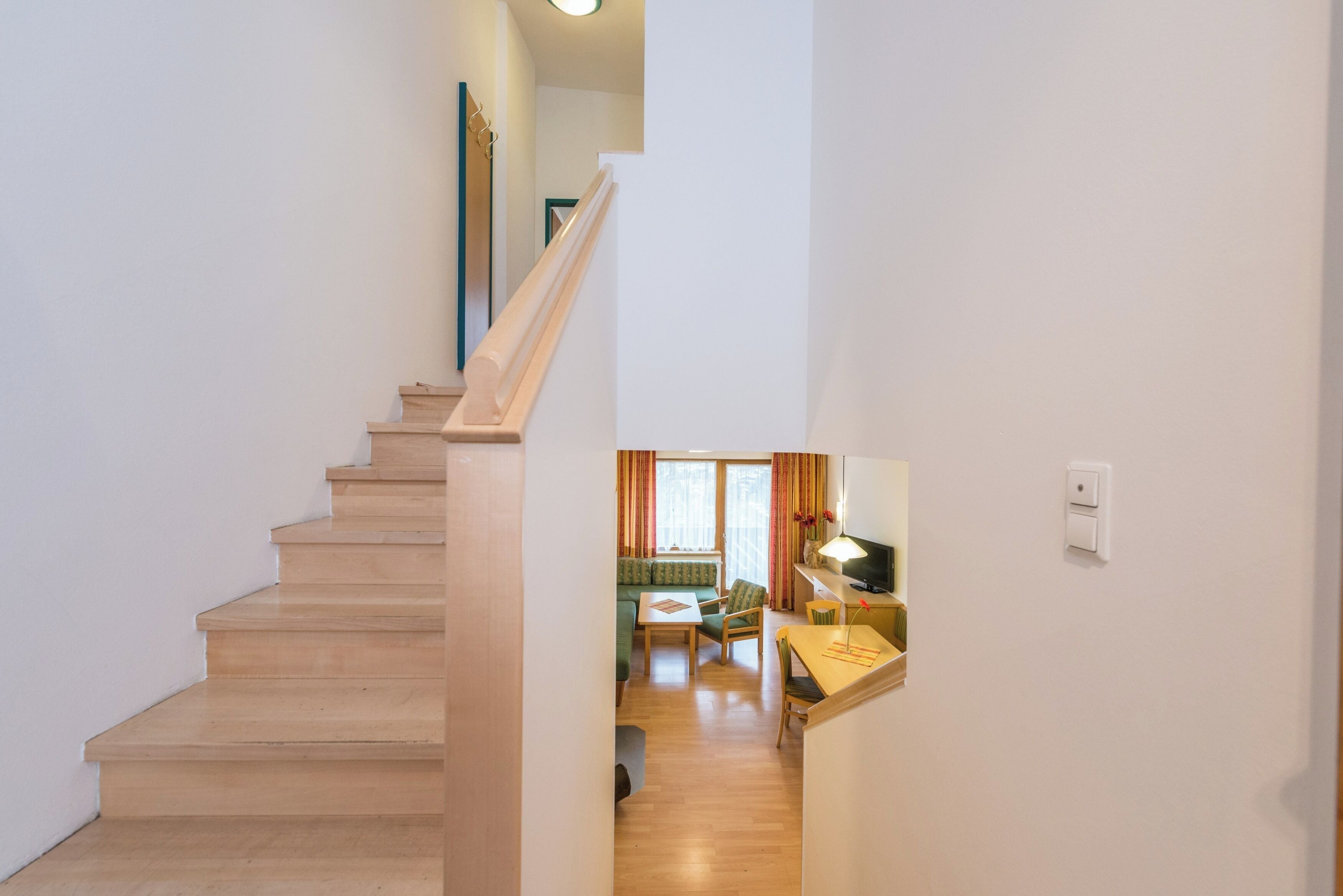 A staircase leading to a living area with a sofa, table, and a TV.