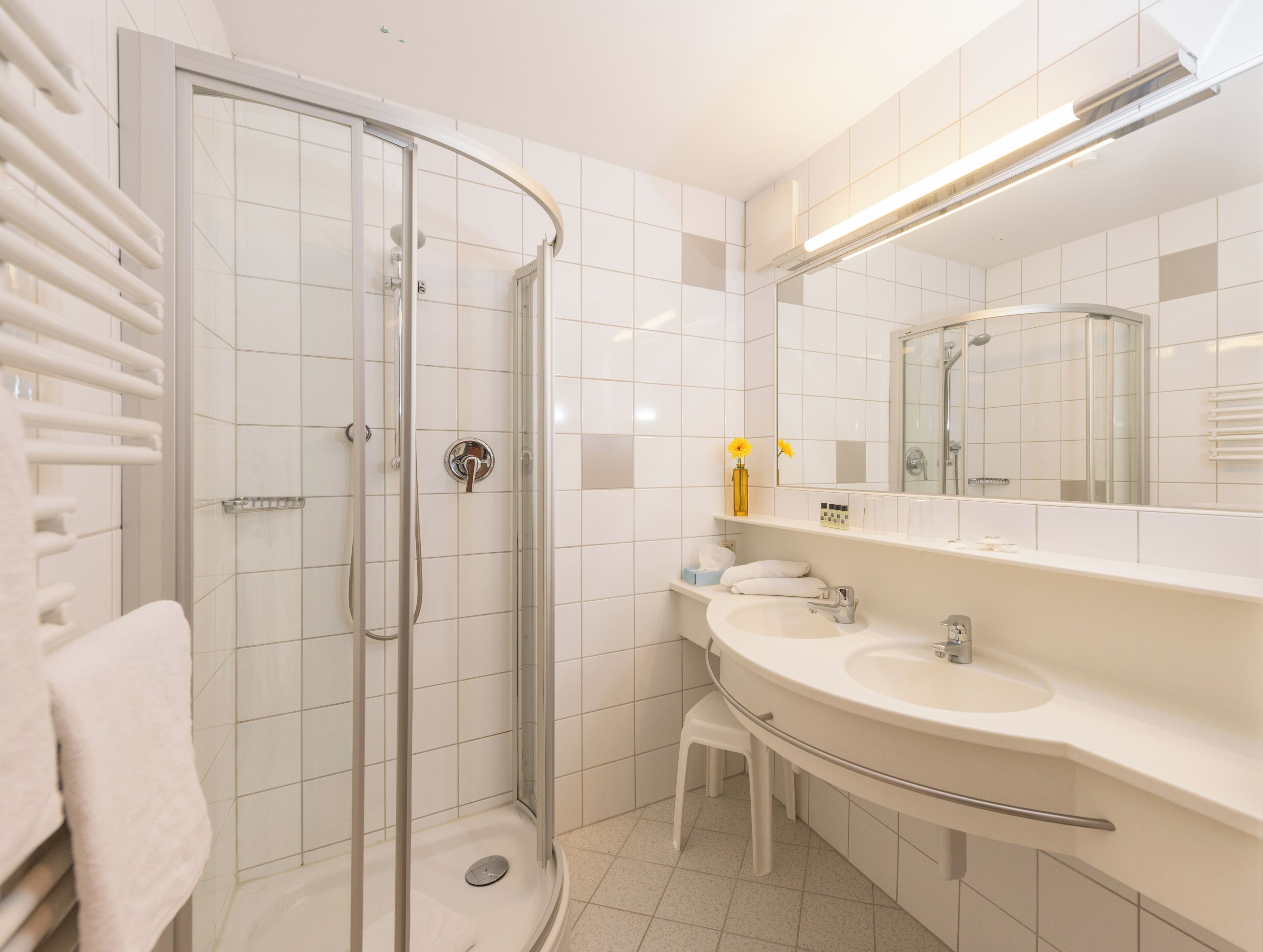 Ein modernes Badezimmer mit einer Glasdusche, einem Waschtisch und einem großen Spiegel.