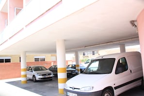 Un estacionamiento con varios coches bajo un área techada.