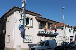 Un hôtel doté d’un balcon, d’une enseigne indiquant qu’il s’agit d’un hôtel Quasar, et d’un panneau de signalisation indiquant la présence d’un parking à proximité.