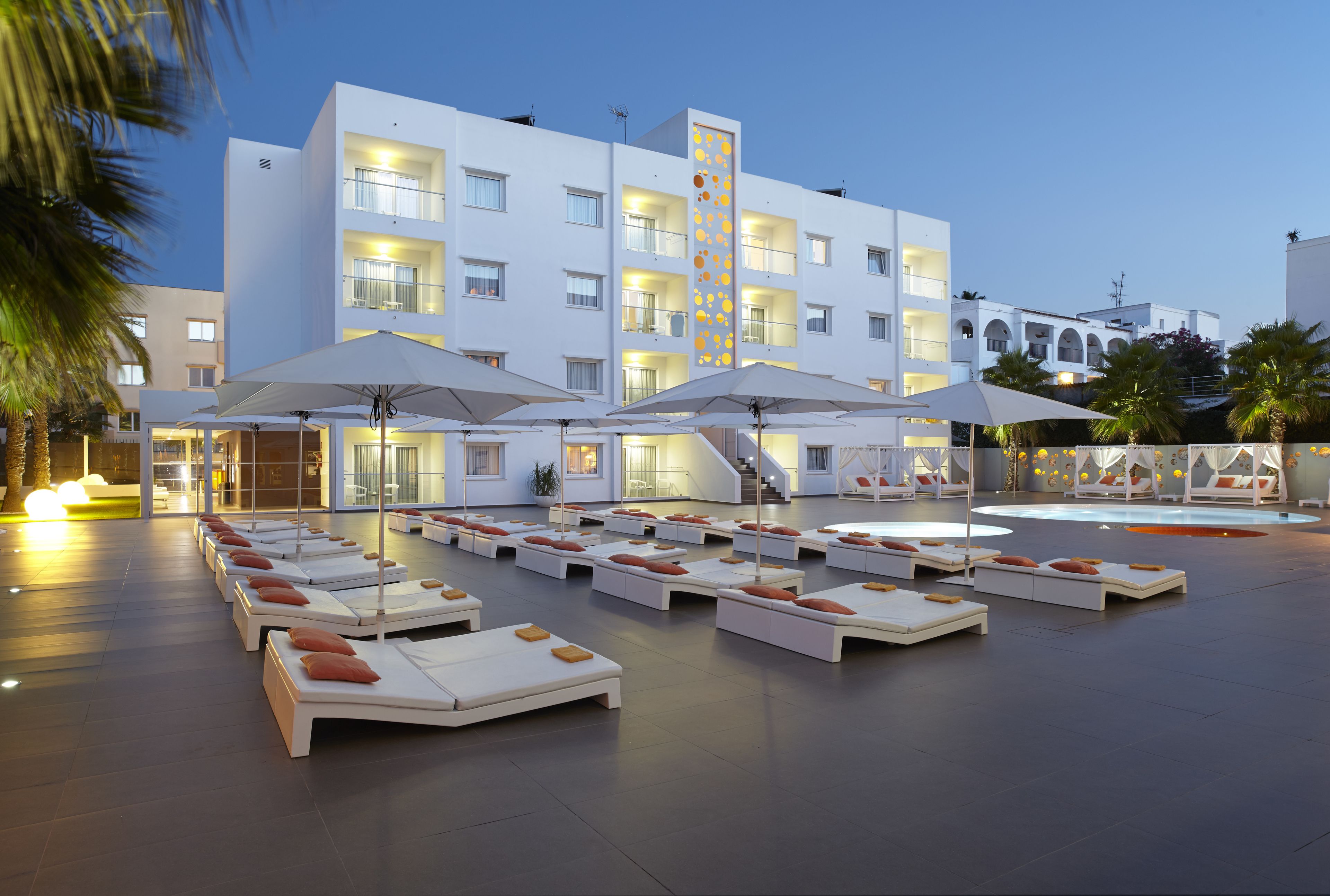 A hotel with multiple lounge areas, outdoor seating, and a modern architectural design.