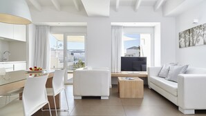 A modern living room with a glass dining table, white sofas, and a TV. - Ibiza Sun Apartments (Sant Josep de sa Talaia)
