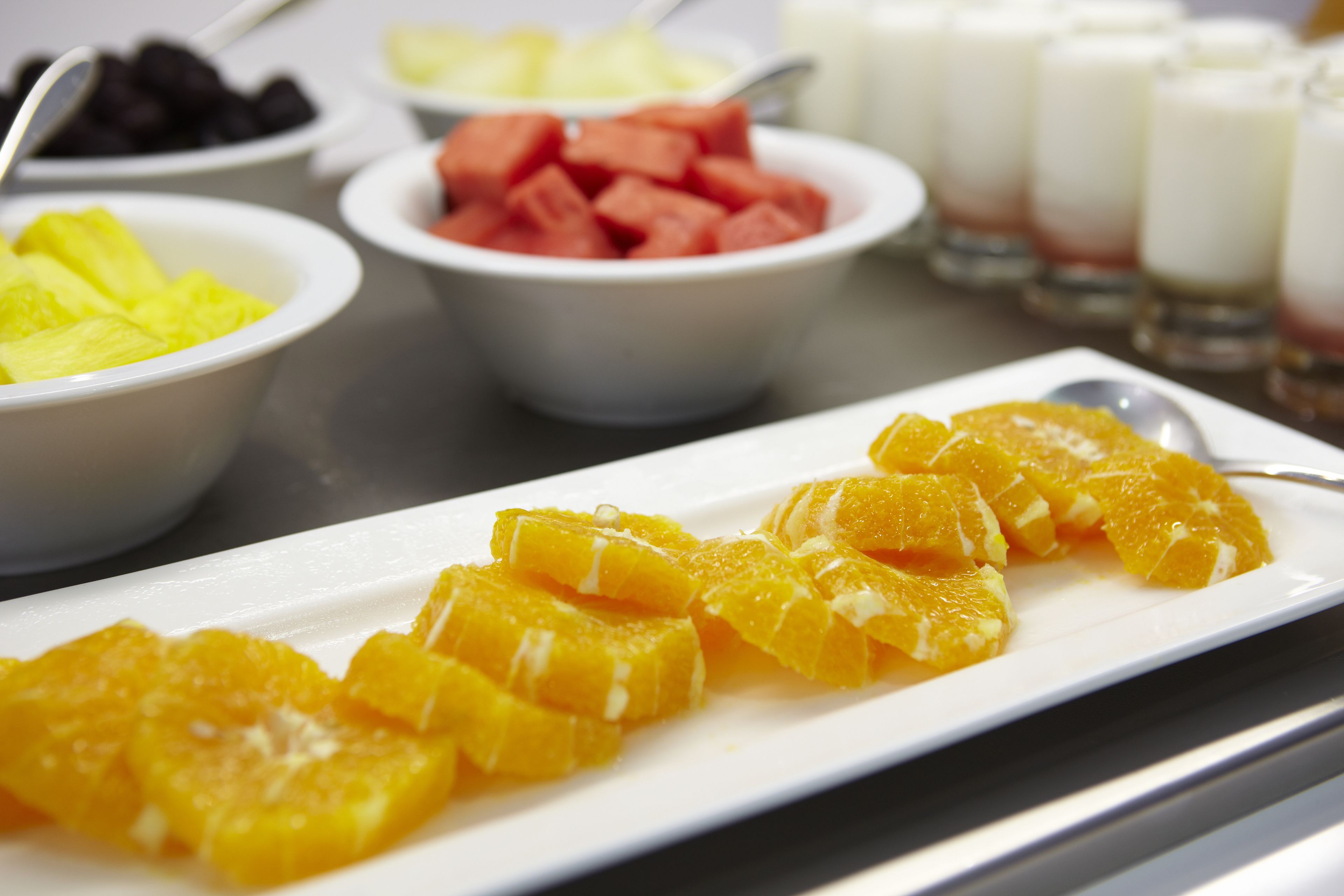 A breakfast buffet with various fruits and a white plate with orange segments.