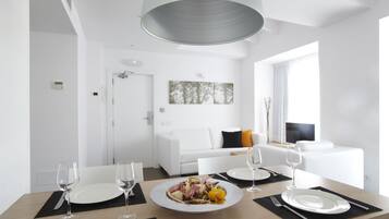 Un comedor moderno y bien iluminado con una mesa de madera dispuesta para dos personas, platos blancos y copas de vino.