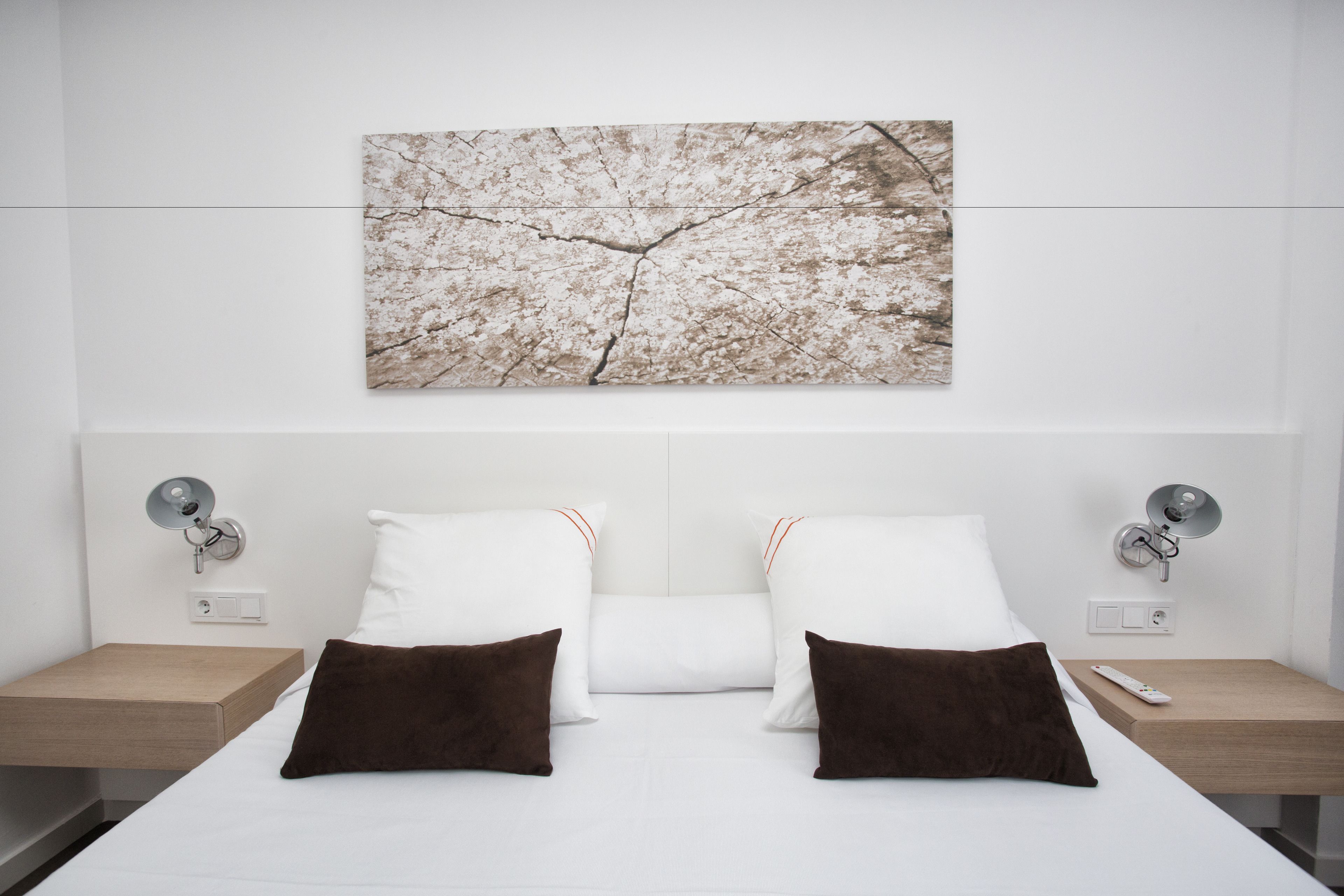Una habitación de hotel moderna con una cama grande, dos mesitas de noche y una obra de arte colgada en la pared.