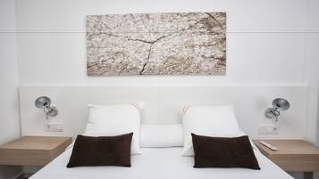 Una habitación de hotel moderna con una cama grande, dos mesitas de noche y una obra de arte colgada en la pared.