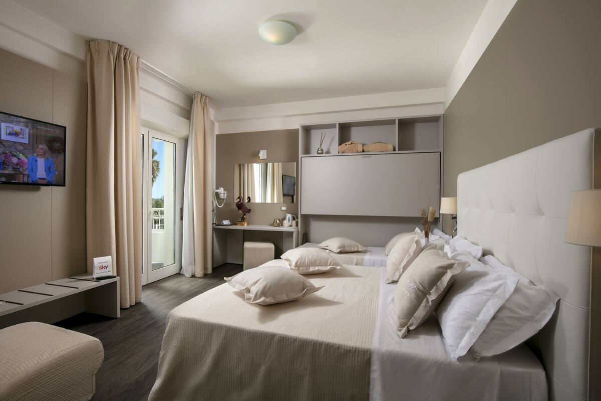 A modern hotel room with a large bed, a desk, and a television.