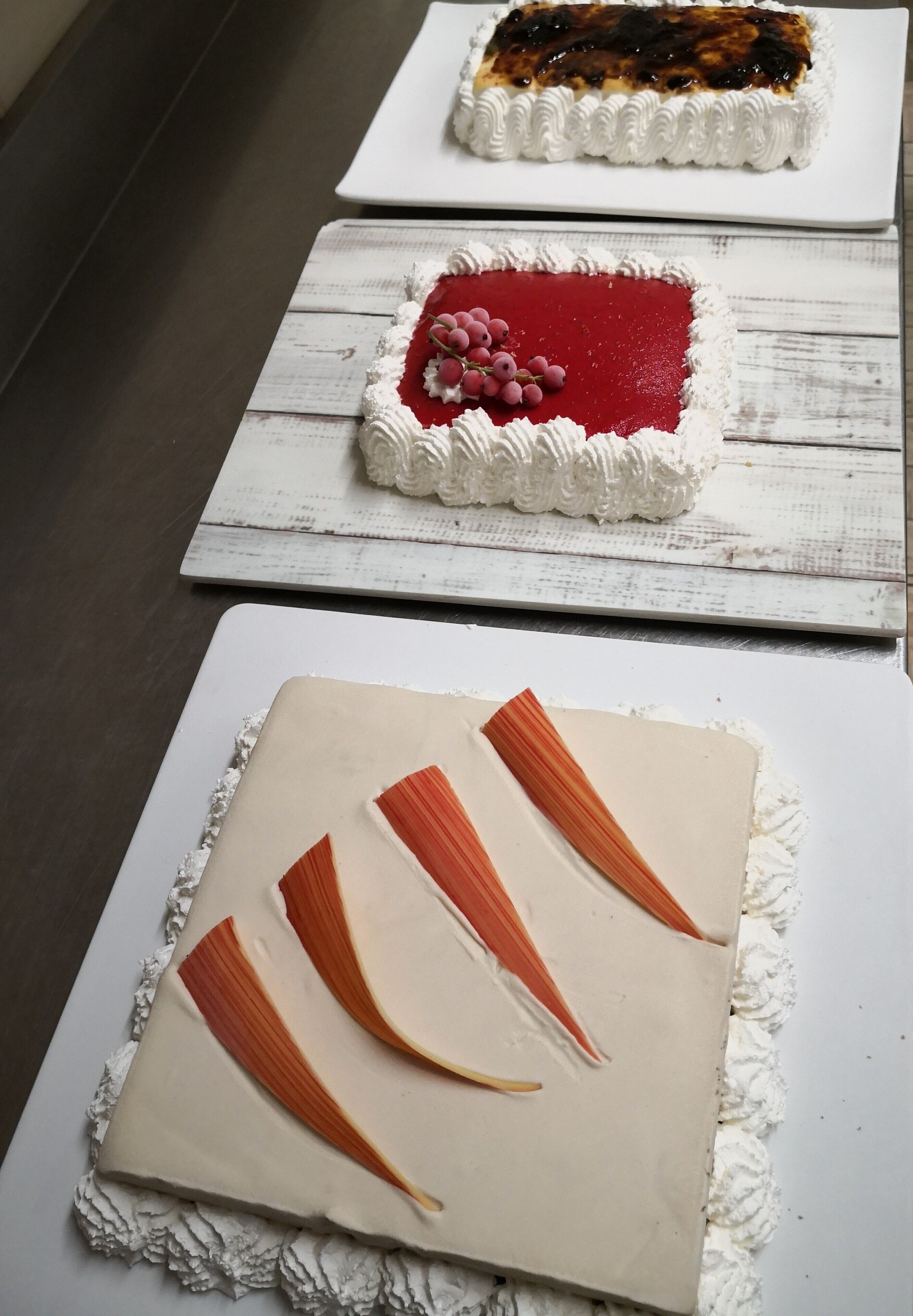 Tre dolci su piatti bianchi con elementi decorativi.