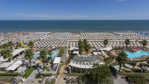 A resort with multiple swimming pools, beach umbrellas, and palm trees. - Hotel Ca' Bianca (Riccione)