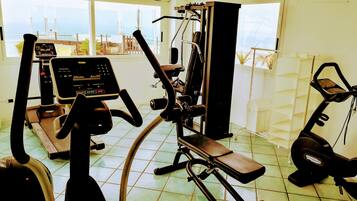 Un gimnasio con máquinas de cardio, equipo de entrenamiento de fuerza y un panel de control.