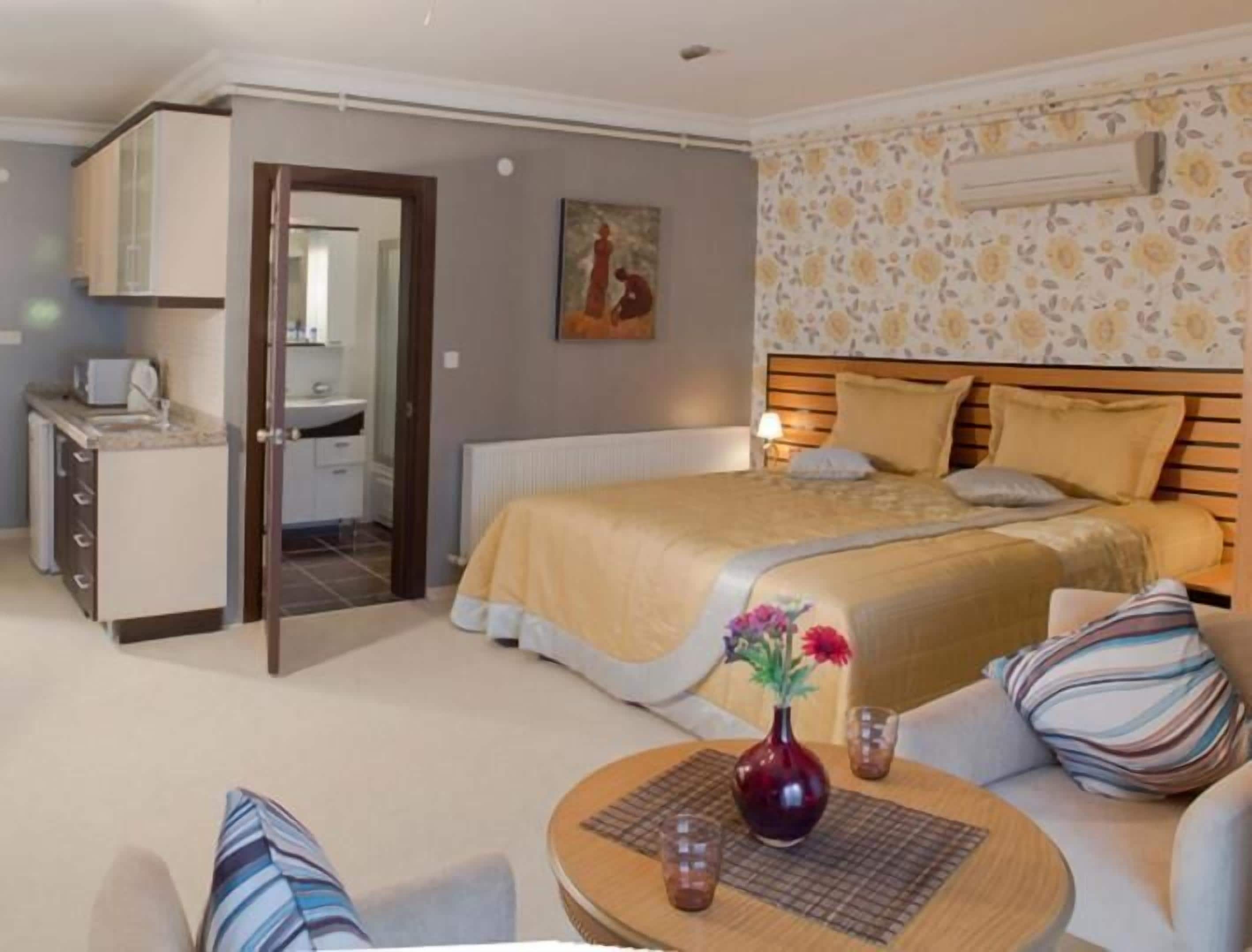 A bedroom with a bed, bedside table, and a small sitting area with a chair and table.