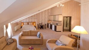 A cozy, well-lit room with a sofa, armchair, and a small table with a lamp. A bed with a headboard and bedside lamps is visible in the background. - The Bosphorus Aparts (Istanbul)