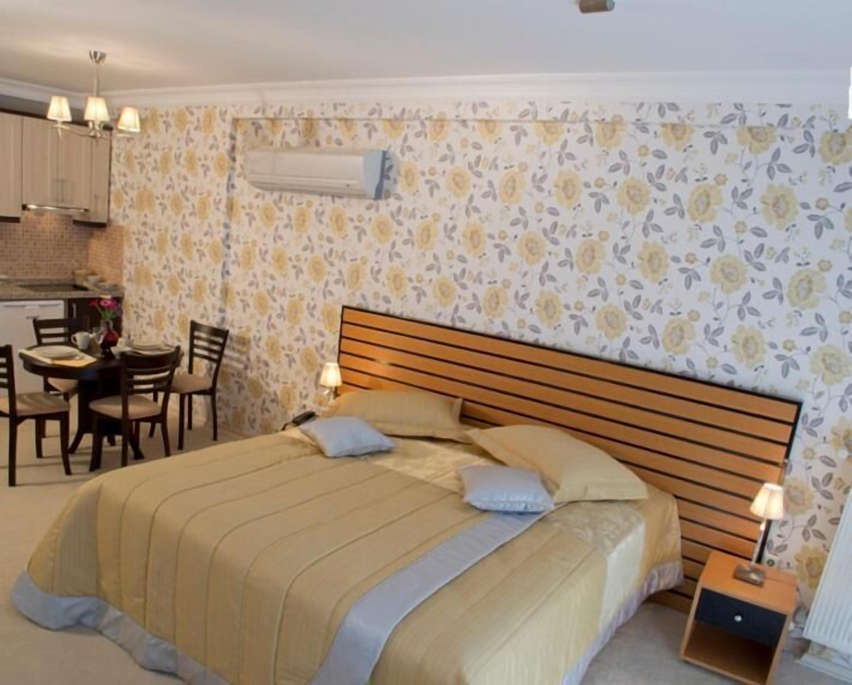 A bedroom with a bed, bedside tables, a desk, and chairs.