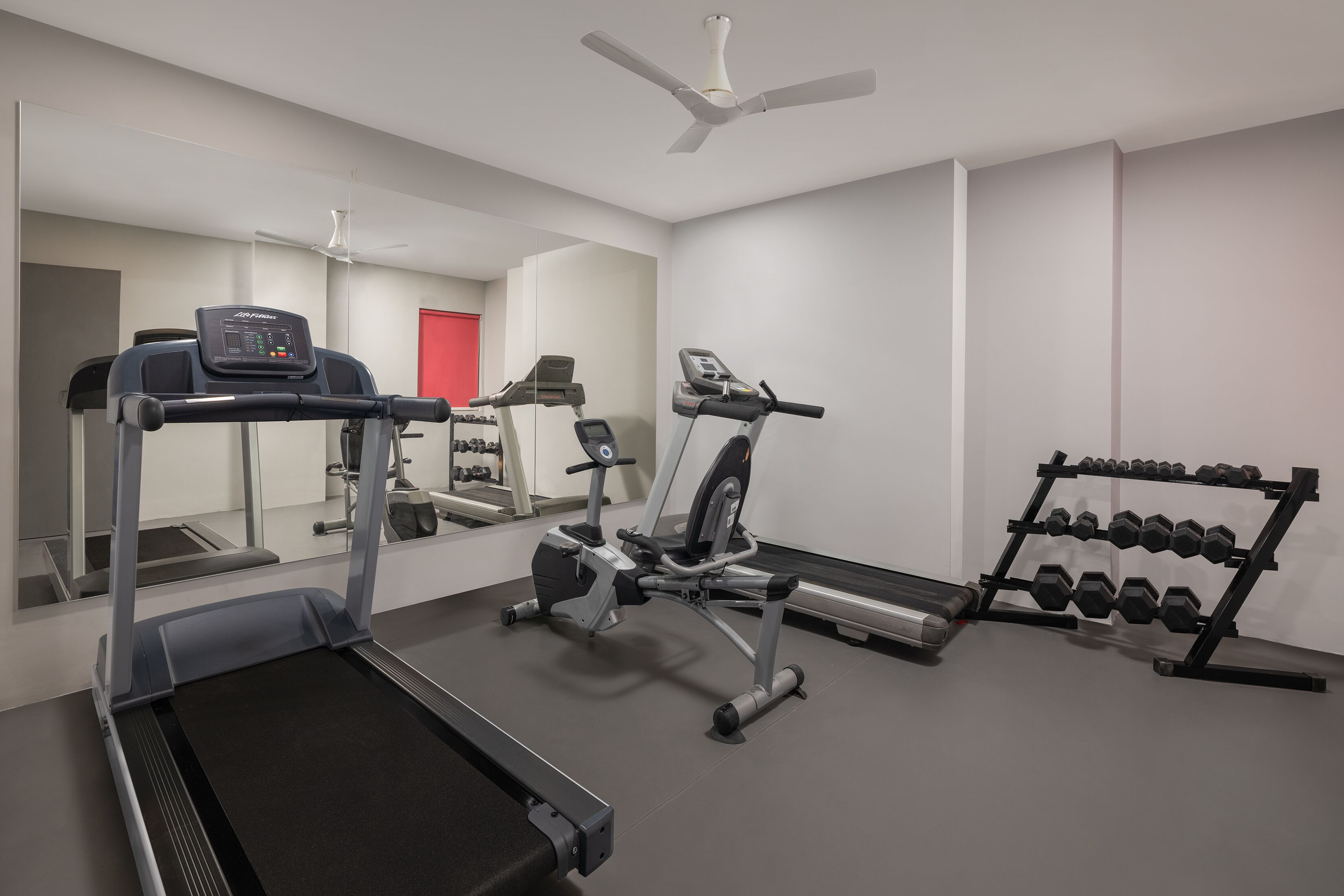 Un gimnasio con cintas de correr, elípticas y un soporte para mancuernas.