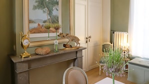 A room with a fireplace, a framed landscape painting, a deer figurine, and a small table with candles. - B&B Mirabel (Bruges)